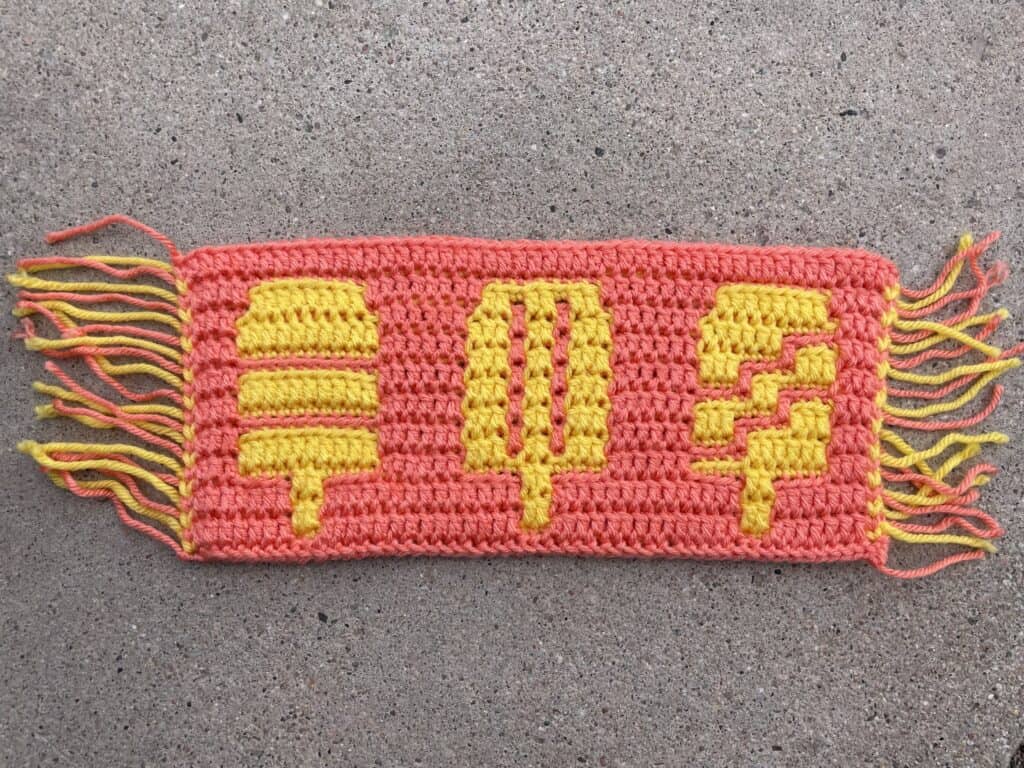 Mosaic crochet design with yellow popsicles on a pink background.