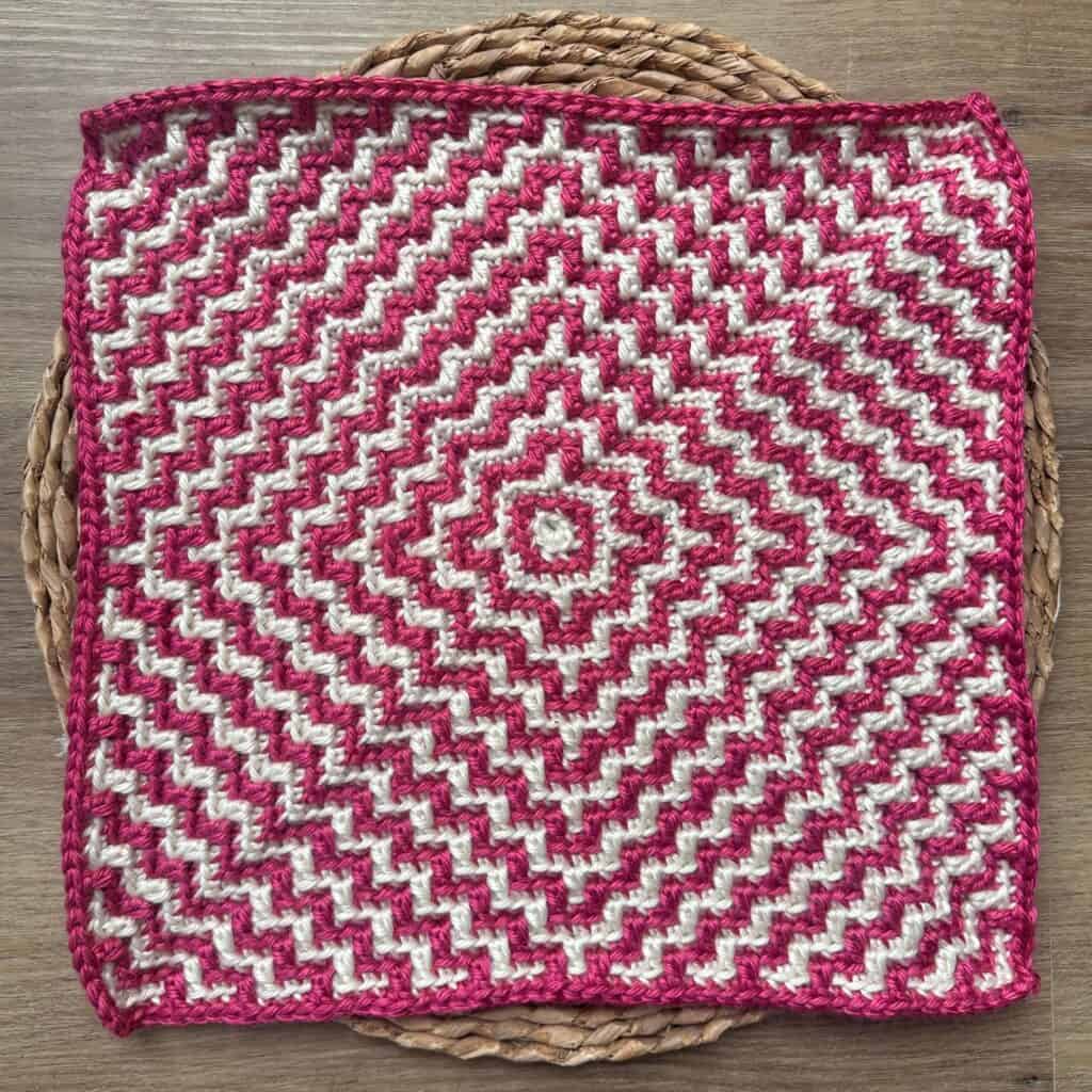 Bright pink and white mosaic crochet square with a geometric ripple pattern. Perfect for home decor.