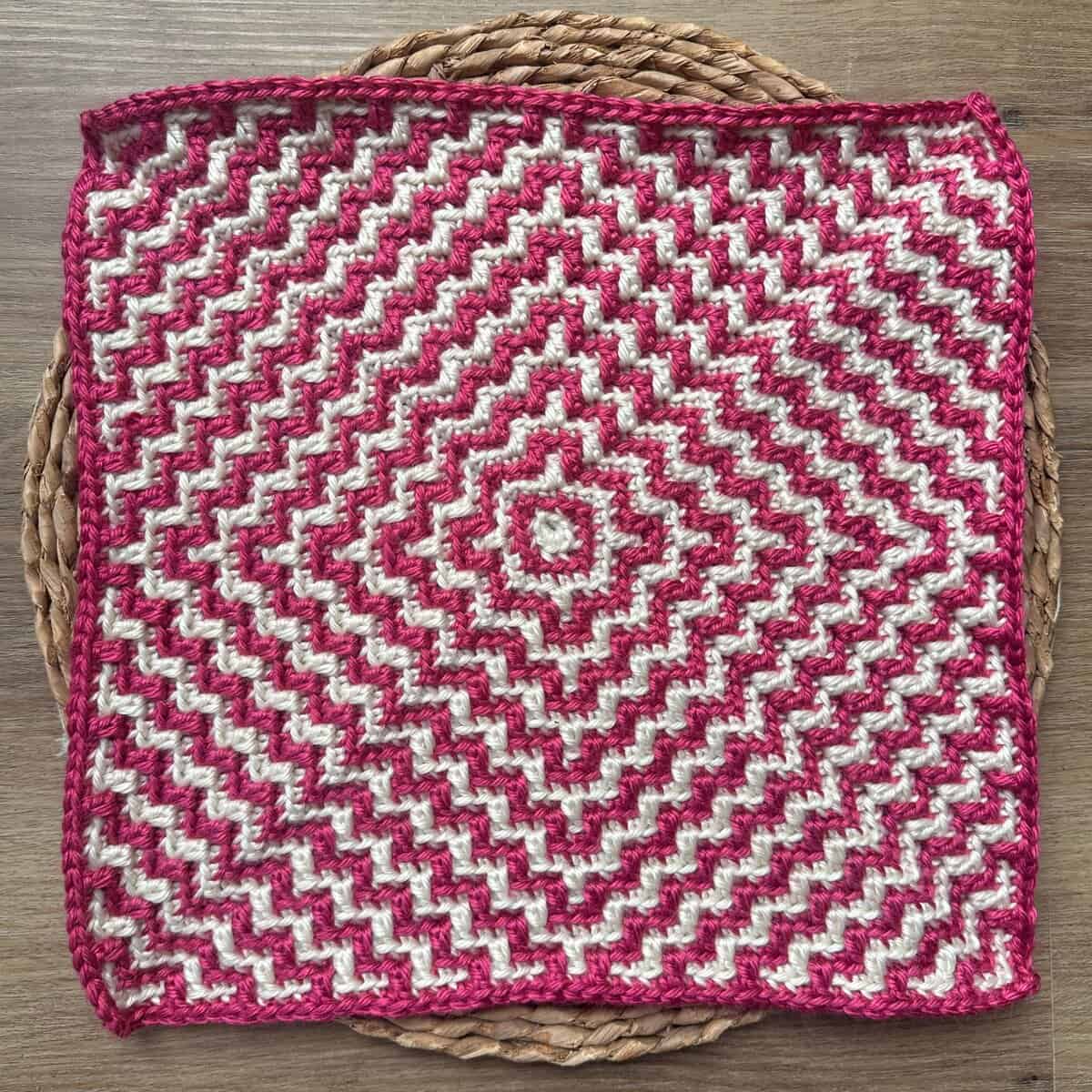 Bright pink and white mosaic crochet square with a geometric ripple pattern. Perfect for home decor.