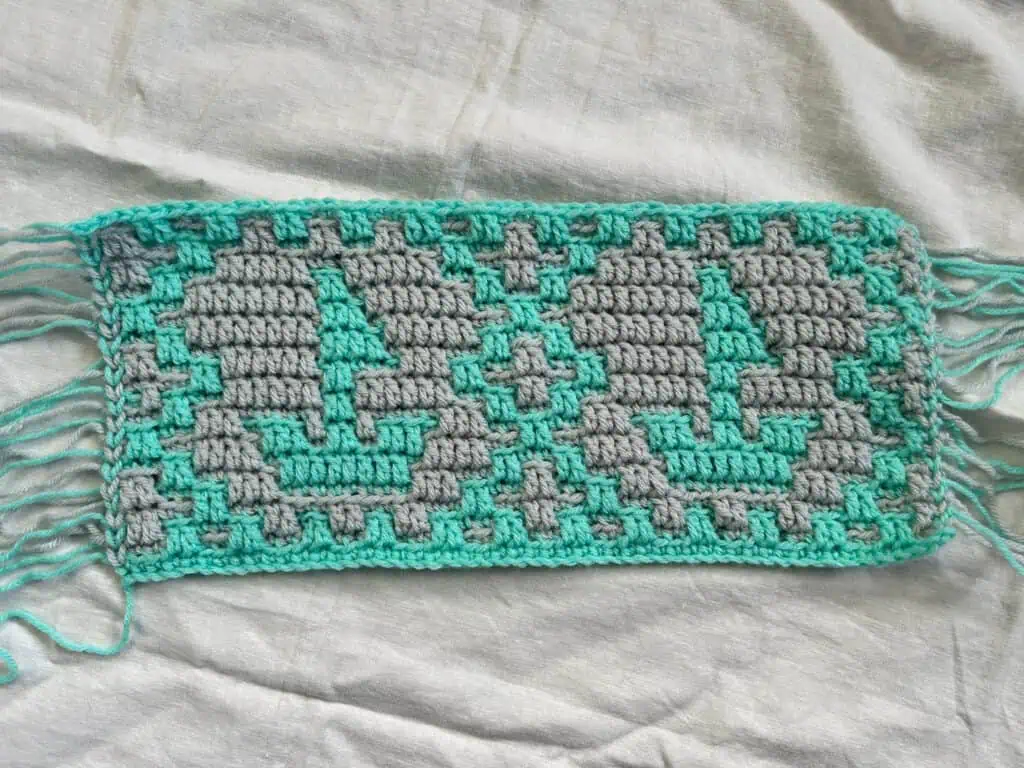 Colorful mosaic crochet sailboats with geometric motifs, in aqua and gray.