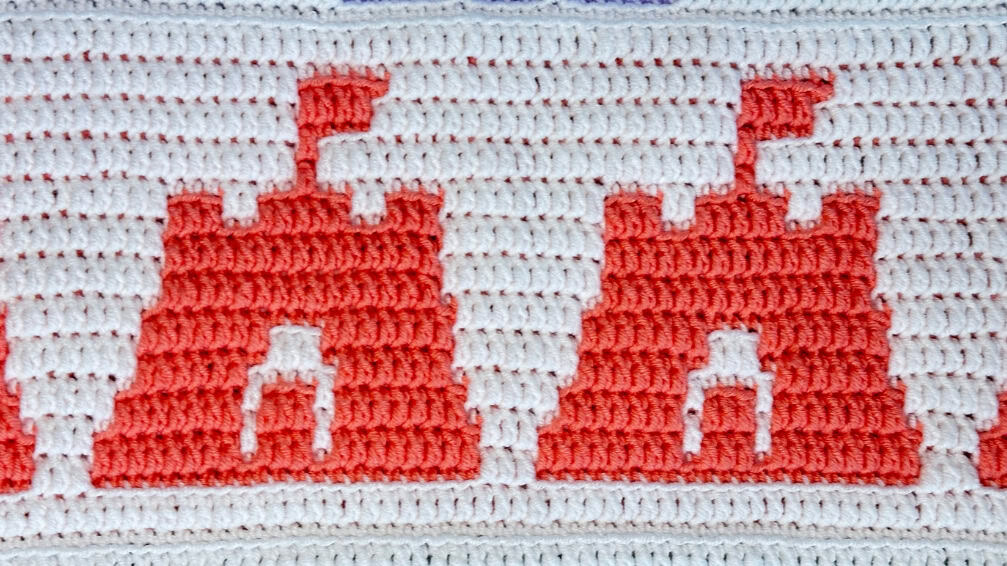 Colorful crochet blanket strip featuring a summer mosaic pattern with red-orange and white sandcastles