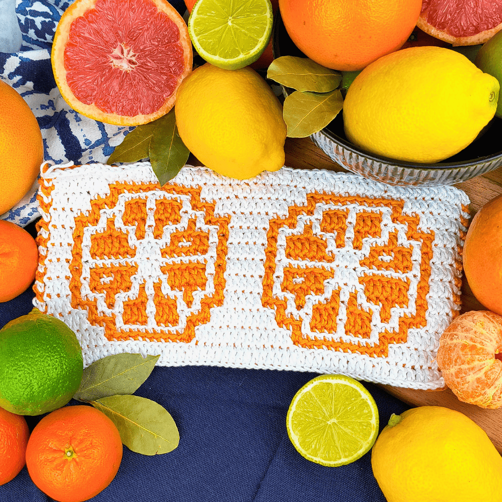 Vibrant mosaic crochet citrus slice design in orange and white, surrounded by fresh citrus fruits