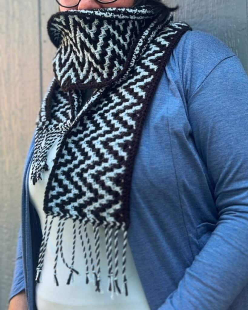 ZigZag mosaic crochet scarf with black and white pattern and fringe detail.