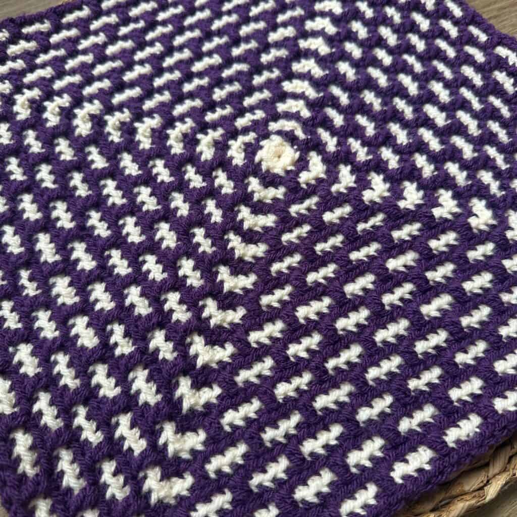 Purple and white woven textile with a geometric pattern, close-up view.