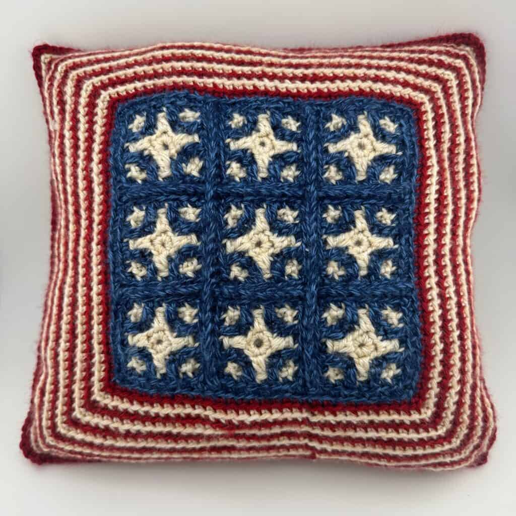 Crochet pillow with patriotic stars in red, white, and blue colors.