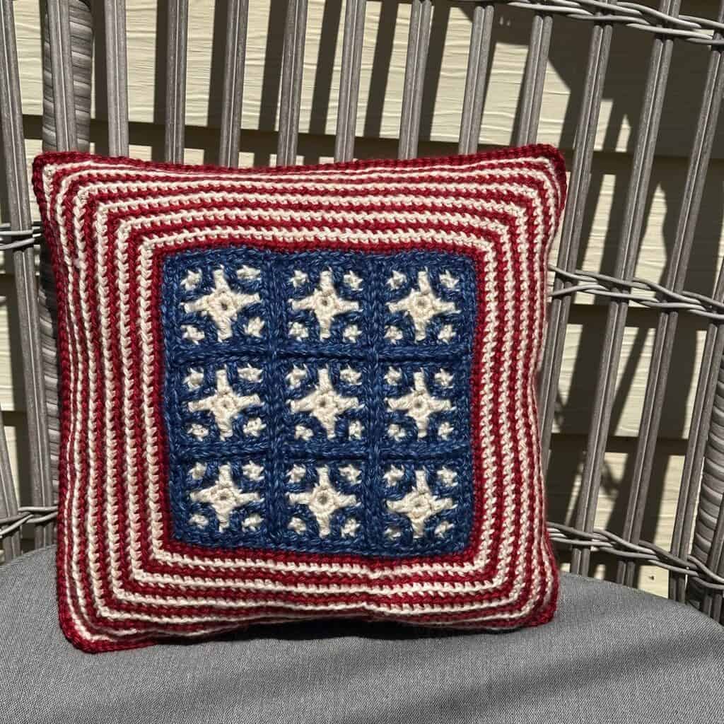 Patriotic crochet pillow with stars and stripes in red, white, and blue for 4th of July.