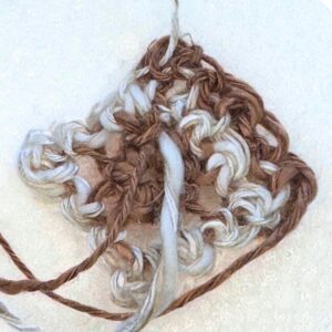 Handcrafted yarn heart with mixed brown and white yarns, symbolizing warmth and creativity.