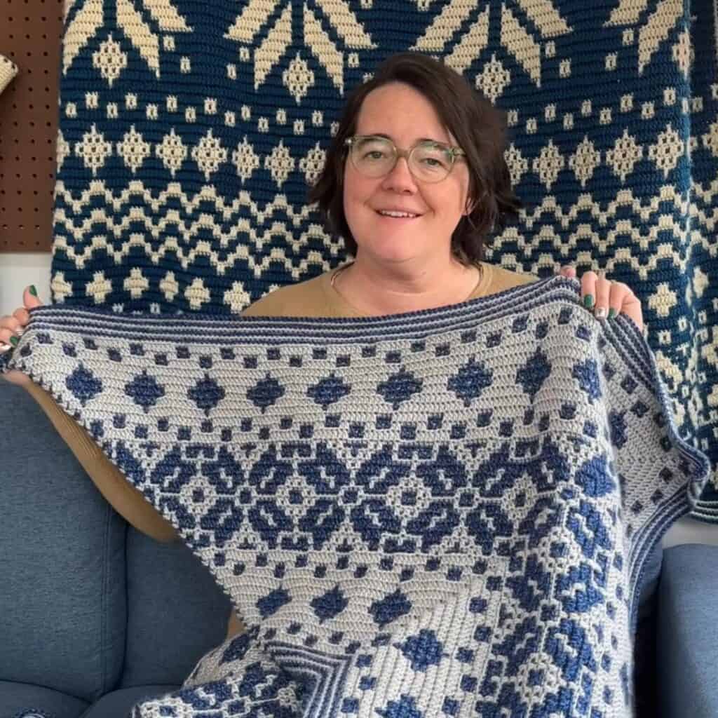 Woman holding a Nordic star mosaic crochet Christmas tree skirt with blue and gray patterns.