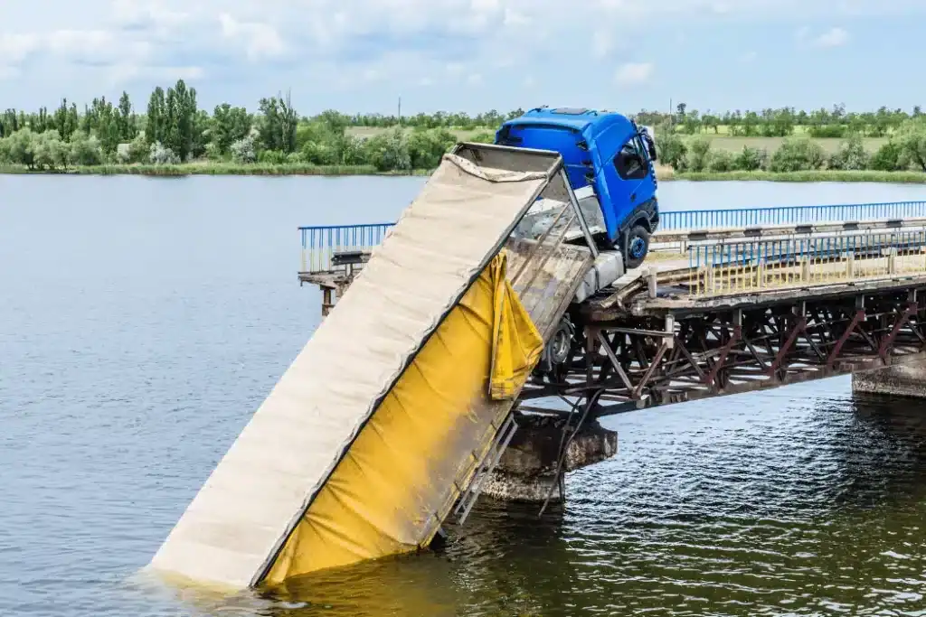 Truck accident, bridge collapse, vehicle submerged in water, transportation incident.