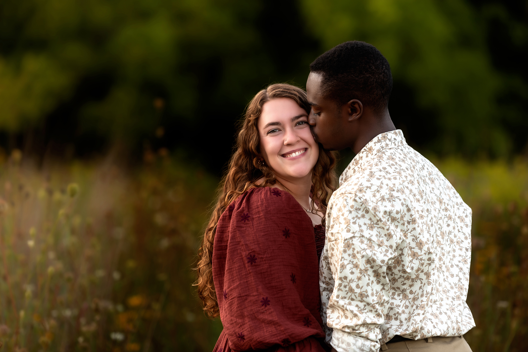man kissing woman on cheek in flower field