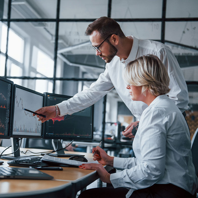 Business analysts analyzing data on multiple computer screens in an office.