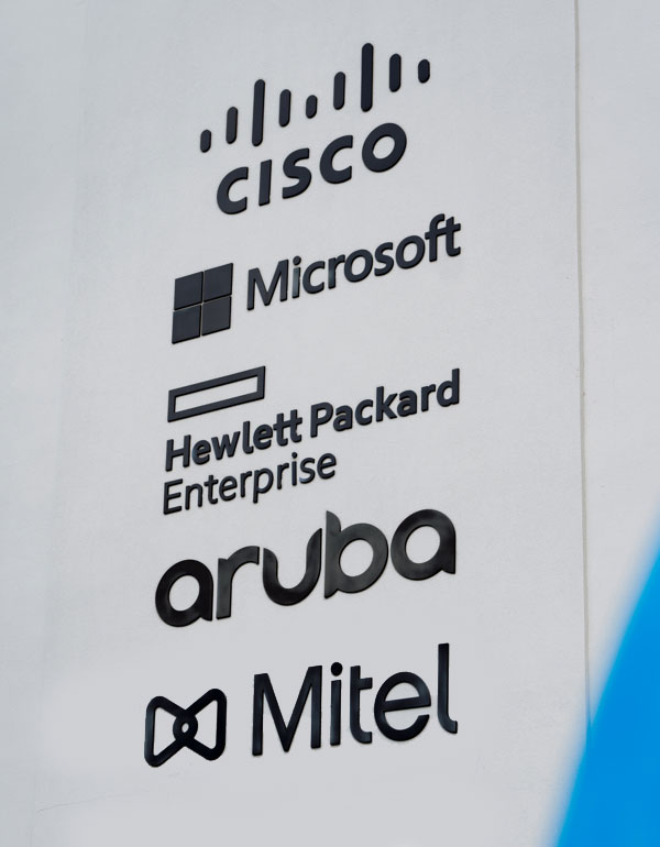 Wall with logos of Cisco, Microsoft, Hewlett Packard, Aruba, and Mitel.
