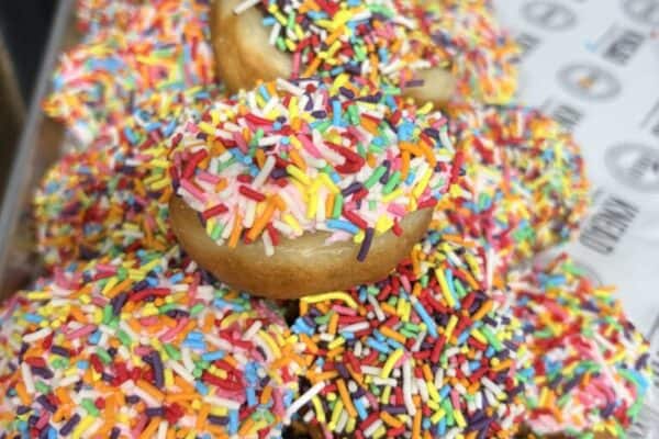 Colorful donuts with rainbow sprinkles stacked high for Tamariki Mini.