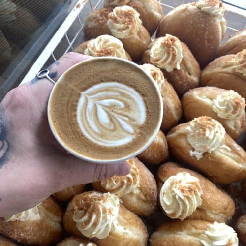 Close-up of creamy topped doughnuts with a latte in a cup at Knead Donuts, New Zealand’s best place for fresh doughnut treats.