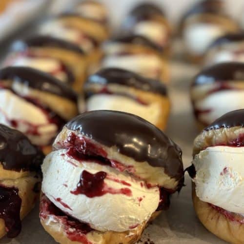 Close-up of decadent Knead Donuts topped with chocolate and filled with ice cream and berry sauce.