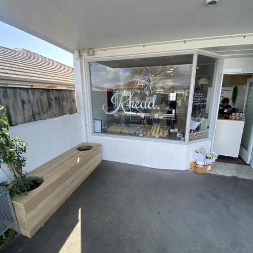 Bright exterior of Knead Donuts bakery in New Zealand with window display of fresh donuts.