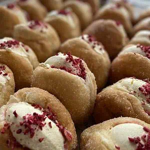 Freshly made donuts with cream and berry topping, perfect for snacks or treat days.