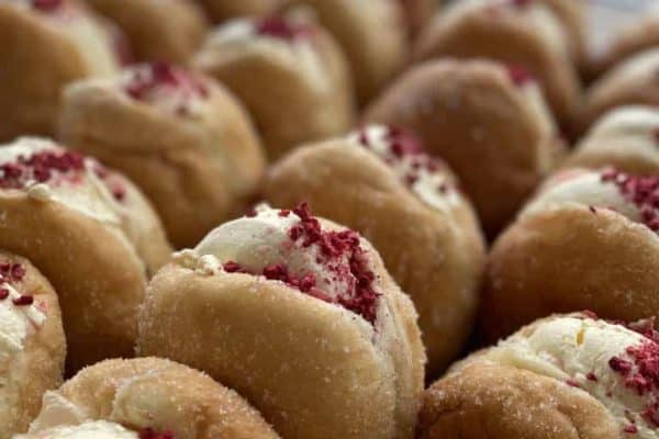Freshly made donuts with cream and berry topping, perfect for snacks or treat days.