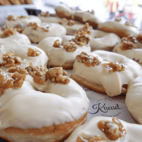 Delicious Donuts topped with walnuts and creamy white icing, baked fresh at Knead Donuts NZ.