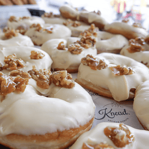 Delicious Donuts topped with walnuts and creamy white icing, baked fresh at Knead Donuts NZ.