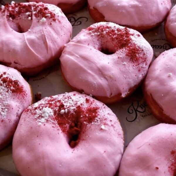 Fresh pink glazed donuts topped with red sprinkles, perfect for a sweet treat.