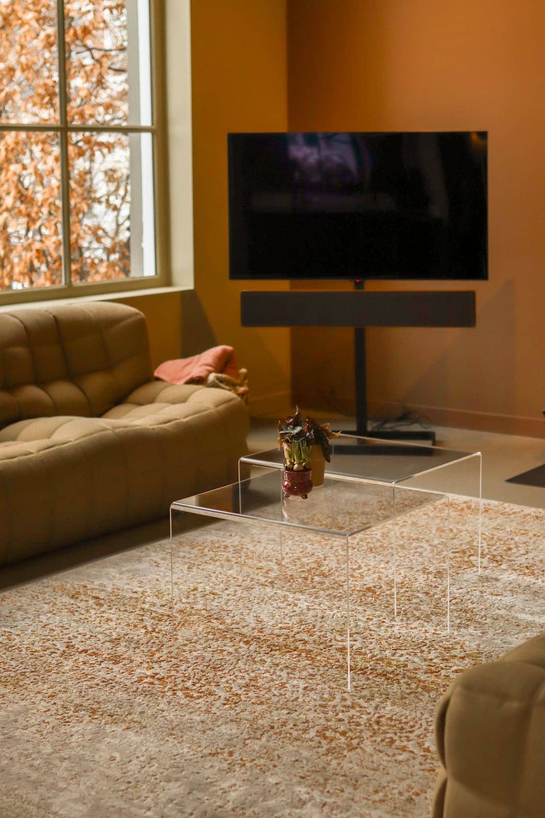 Moderne glazen salontafel 'Arc Zen' in woonkamer met tv en bank.