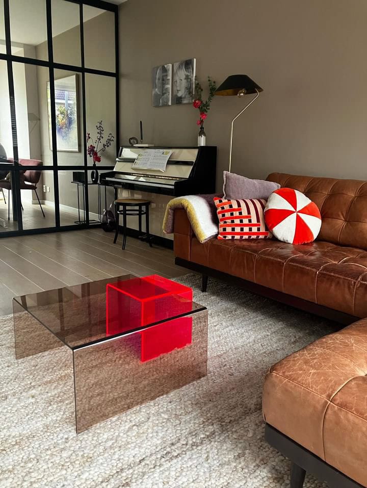 Gezellige woonkamer met piano, glazen salontafel en comfortabele bank.