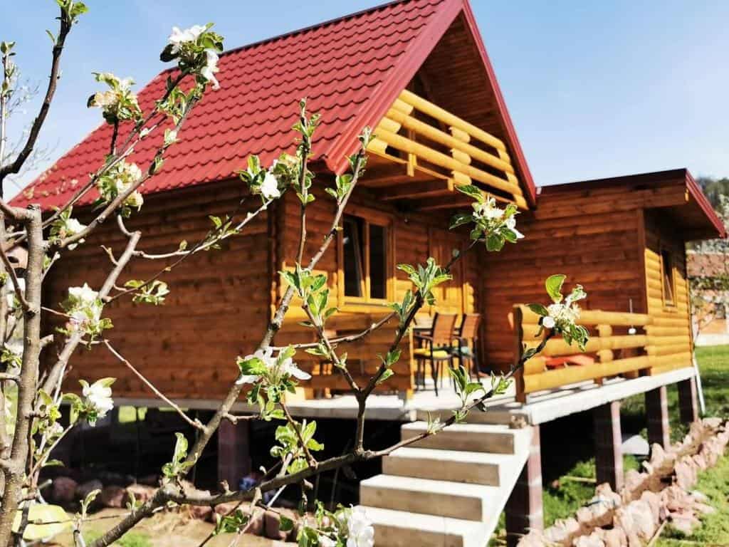 Drvena kuća "Una" u Kulen Vakufu s cvjetnim granama u prvom planu, tradicionalan ambijent s modernim sadržajima.