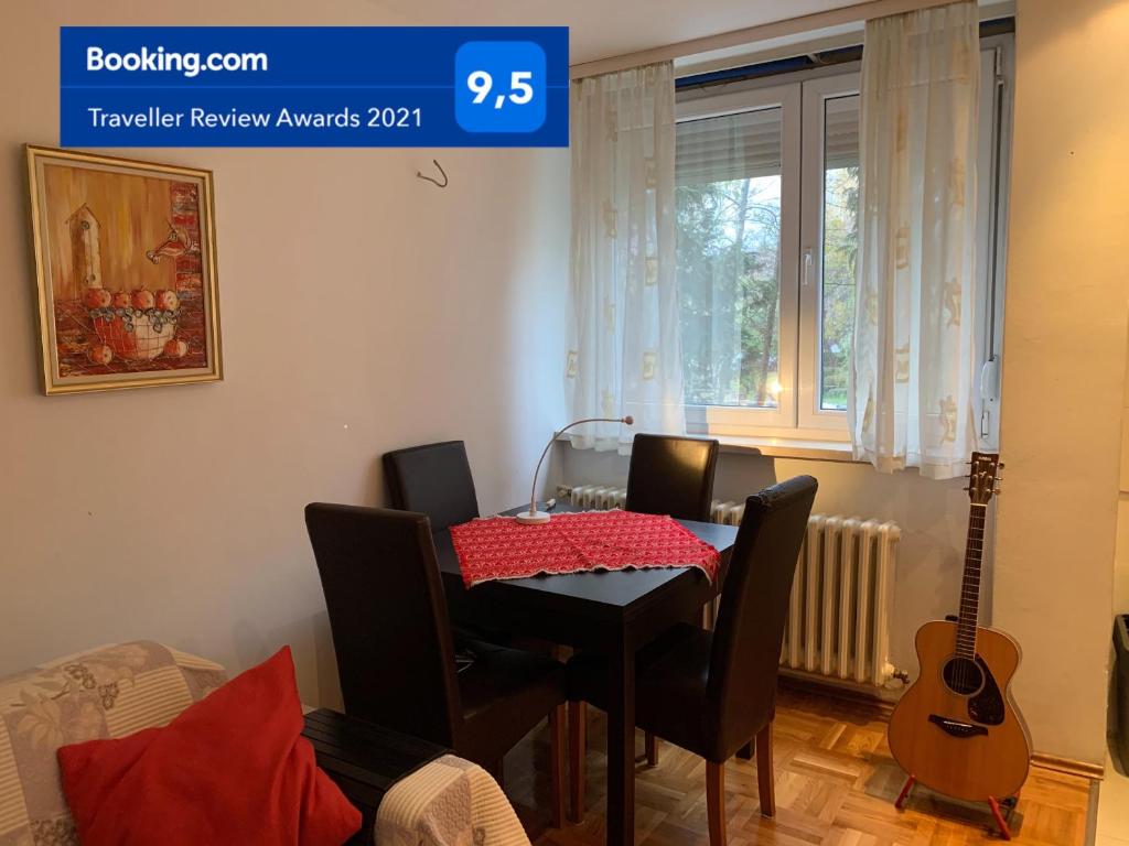 Moderno uređena dnevna soba s drvenim stolom, stolicama i akustičnom gitarom, dio Apartmana Olivia u Banjoj Luci.