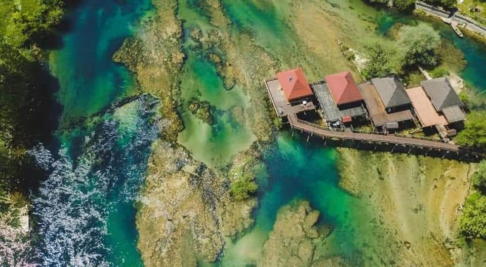 Predivan pogled na bungalove uz rijeku u Bosanskoj Krupi, okružene kristalno čistom vodom i prirodnim ljepotama.