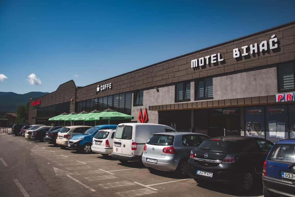Vanjski izgled Motela Bihać s parkingom ispred, s natpisom "Motel Bihać" na fasadi, okružen planinskim pejzažem u pozadini.