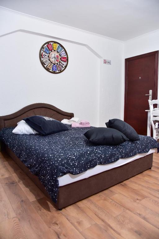 Moderno uređena soba u Apartmanima Koko s udobnim bračnim krevetom i dekorativnim zidnim satom.