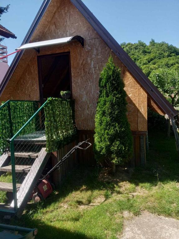 Mala drvena vikendica Alfa Apartman Kulen Vakuf s uređenim travnjakom i terasom u prirodnom okruženju.