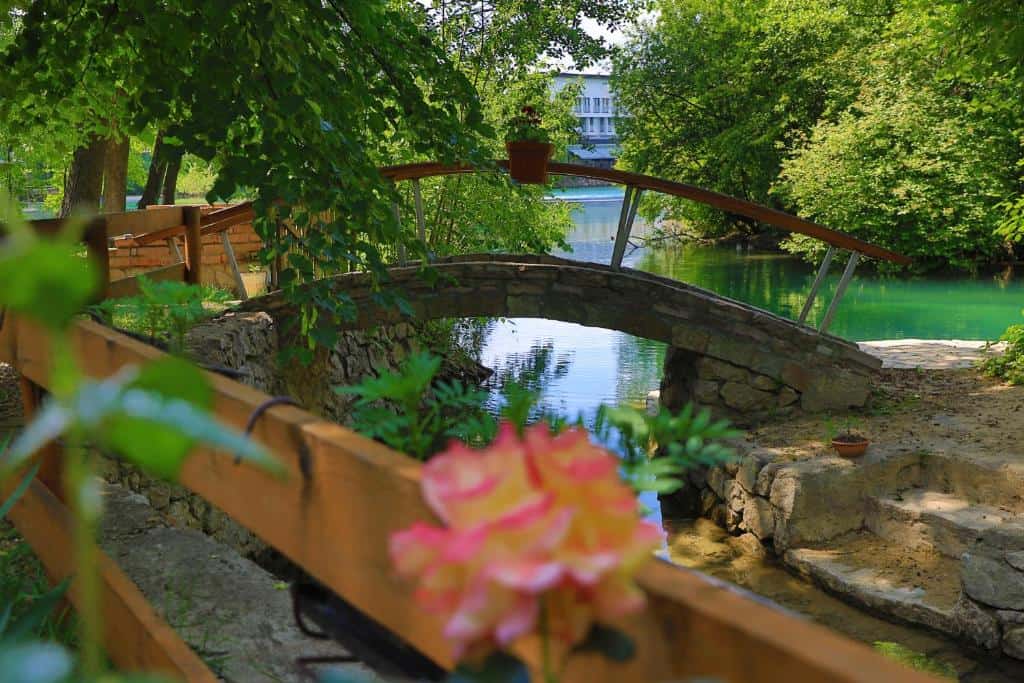 Kameni mostić u prirodnom okruženju s pogledom na rijeku i zelenilo, idealno mjesto za opuštanje i uživanje u prirodi.