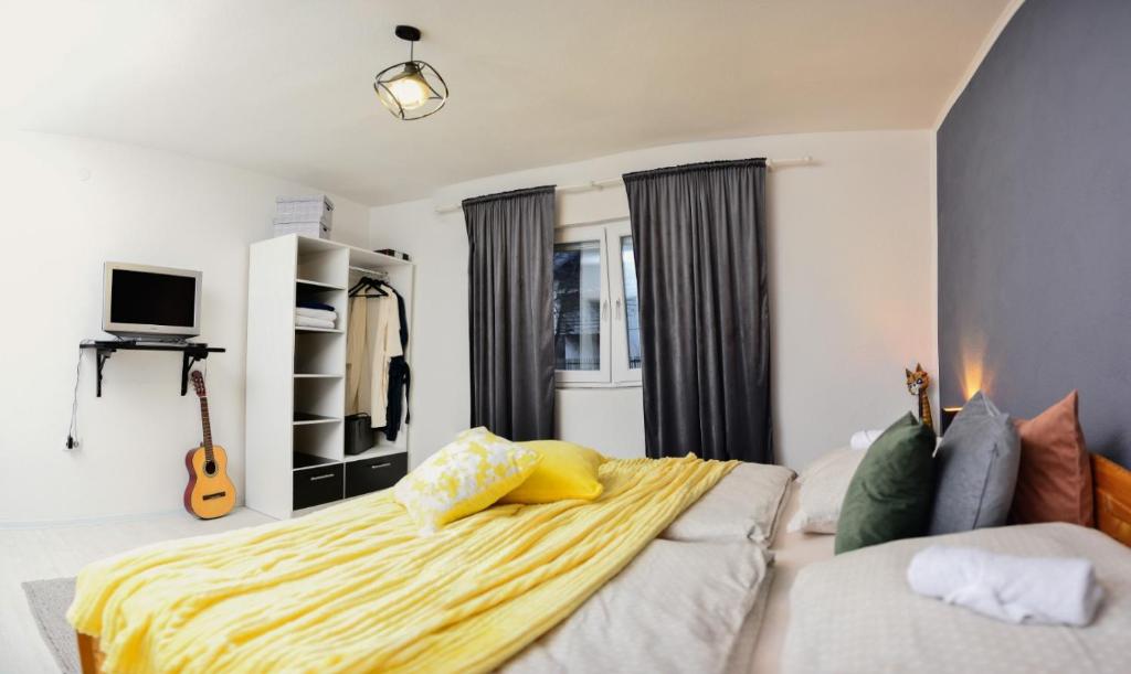 Prostrana spavaća soba u apartmanu Stela1 Drvar s modernim dekorom i žutim prekrivačem