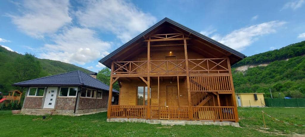 Drvena kuća na Ranču Sunshine Ripač, okružena prirodom i zelenilom, idealna za opuštanje i odmor u prirodi.