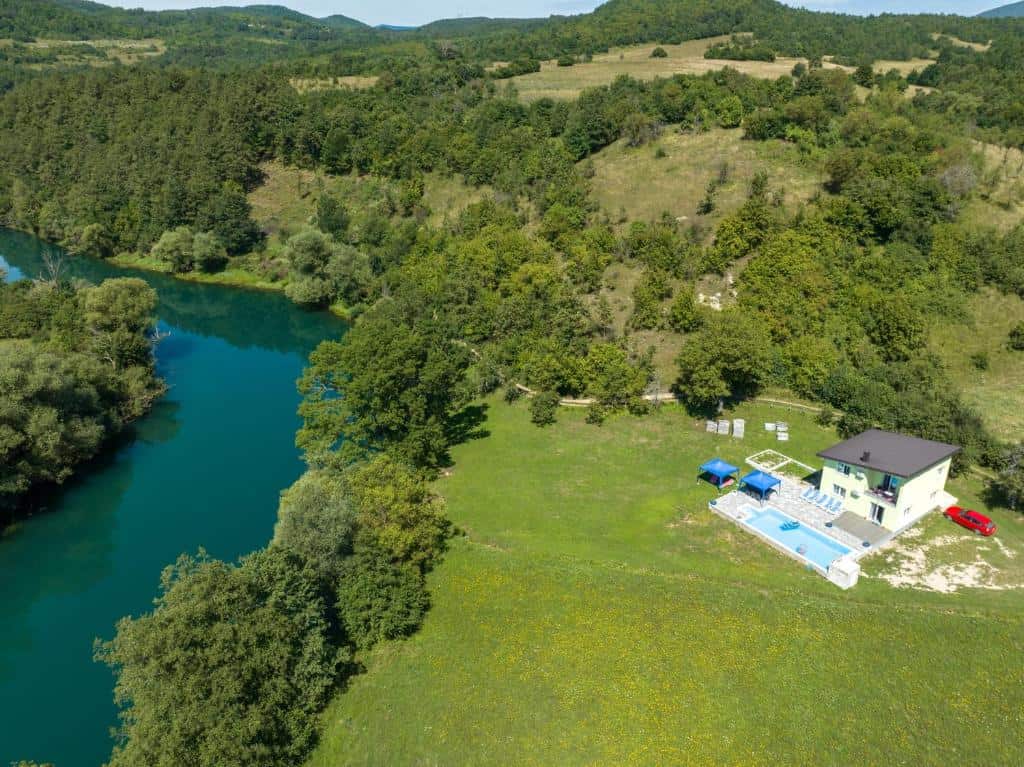 Pogled iz zraka na Green Oasis Bihać s privatnim bazenom, okružen šumom i rijekom u mirnom prirodnom okruženju.