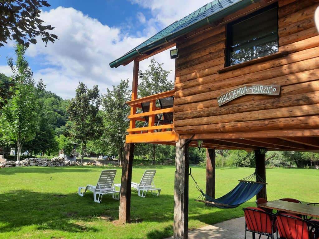 Drvena kuća Hacienda Burzić u Kulen Vakufu s prostranim zelenim vrtom, ležaljkama i visećom mrežom.