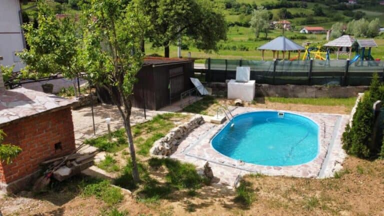 Pogled na dvorište Haus Mali Bihać s privatnim bazenom, dječjim igralištem i prirodnim okruženjem.