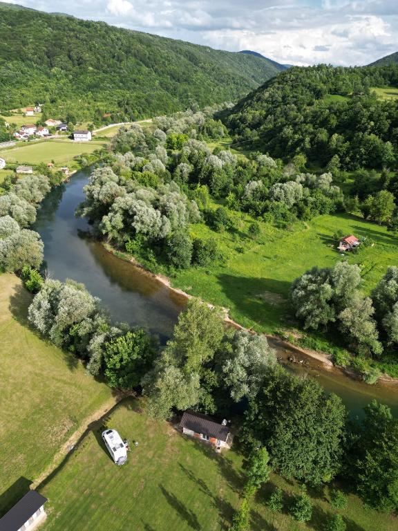 Pogled iz zraka na Camping Status Quo u Kulen Vakufu smješten uz rijeku i okružen zelenim brežuljcima i prirodom.