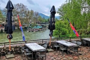 Vanjski prostor za sjedenje u restoranu Kazamat, sa pogledom na rijeku Vrbas, okružen zelenilom i istorijsku tvrđavu Kastel, Banja Luka.