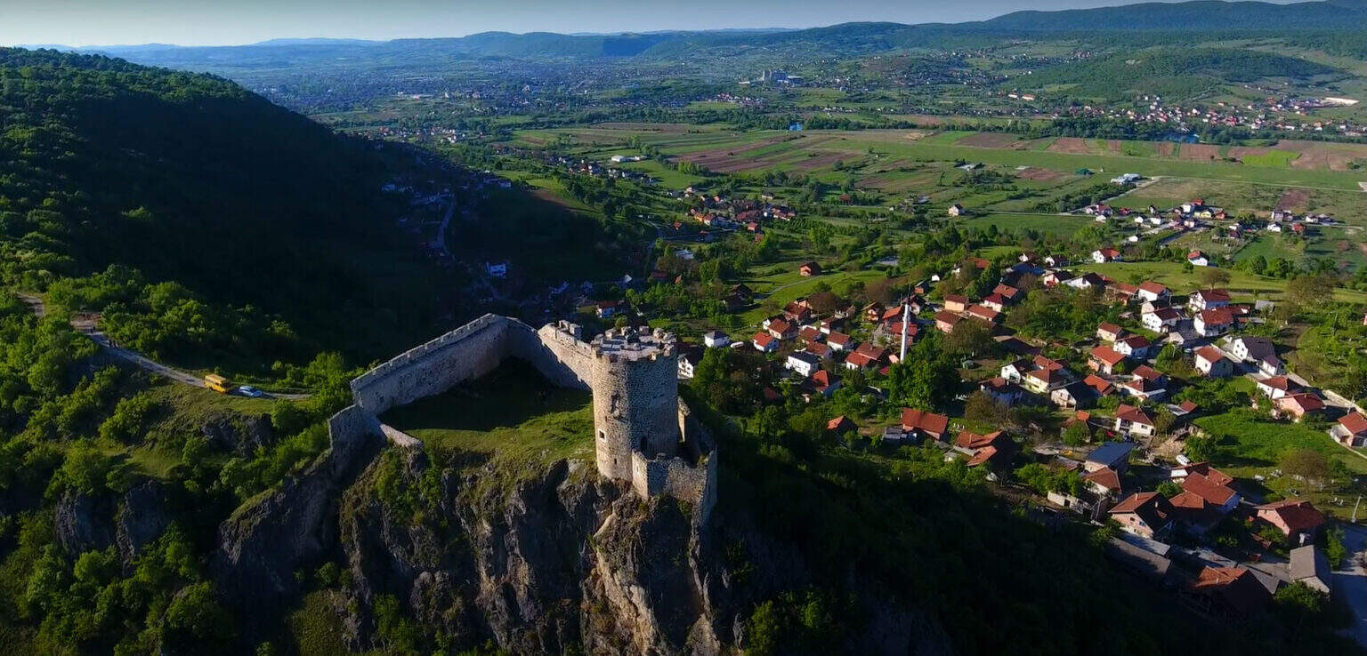 "Tvrđava Sokolac u Bihaću, okružena bujnom zelenom prirodom."