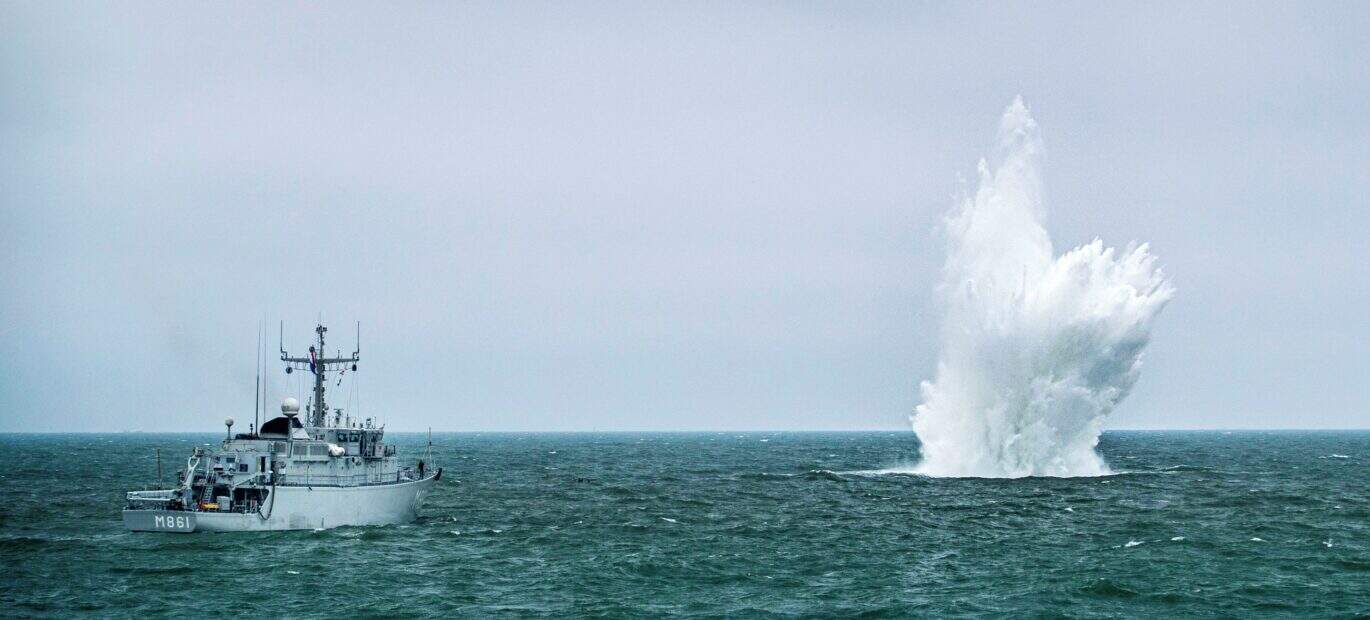 Een mijnenjager van de marine ruimt een explosief op zee. Daarbij ontstaat een grote waterzuil.