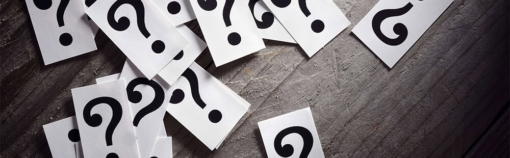 Question marks scattered on dark wooden background.