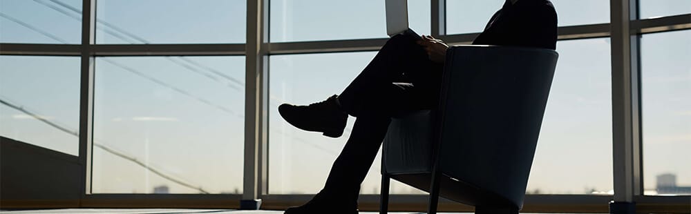 Airport lounge interior with large windows and a seated traveler.