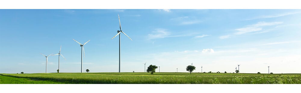 Wind turbines in a green field with blue sky and clouds, renewable energy source, sustainable power.
