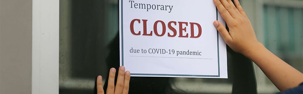 Closed sign on door due to COVID-19 pandemic, indicating temporary closure of business or establishm.