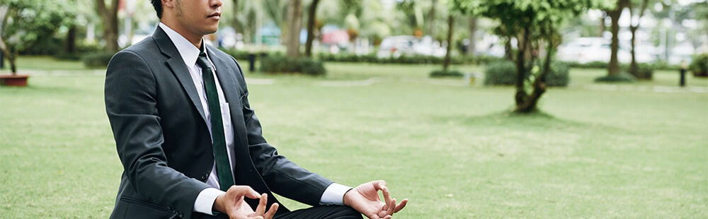 Meditating person in a park, practicing mindfulness outdoors.