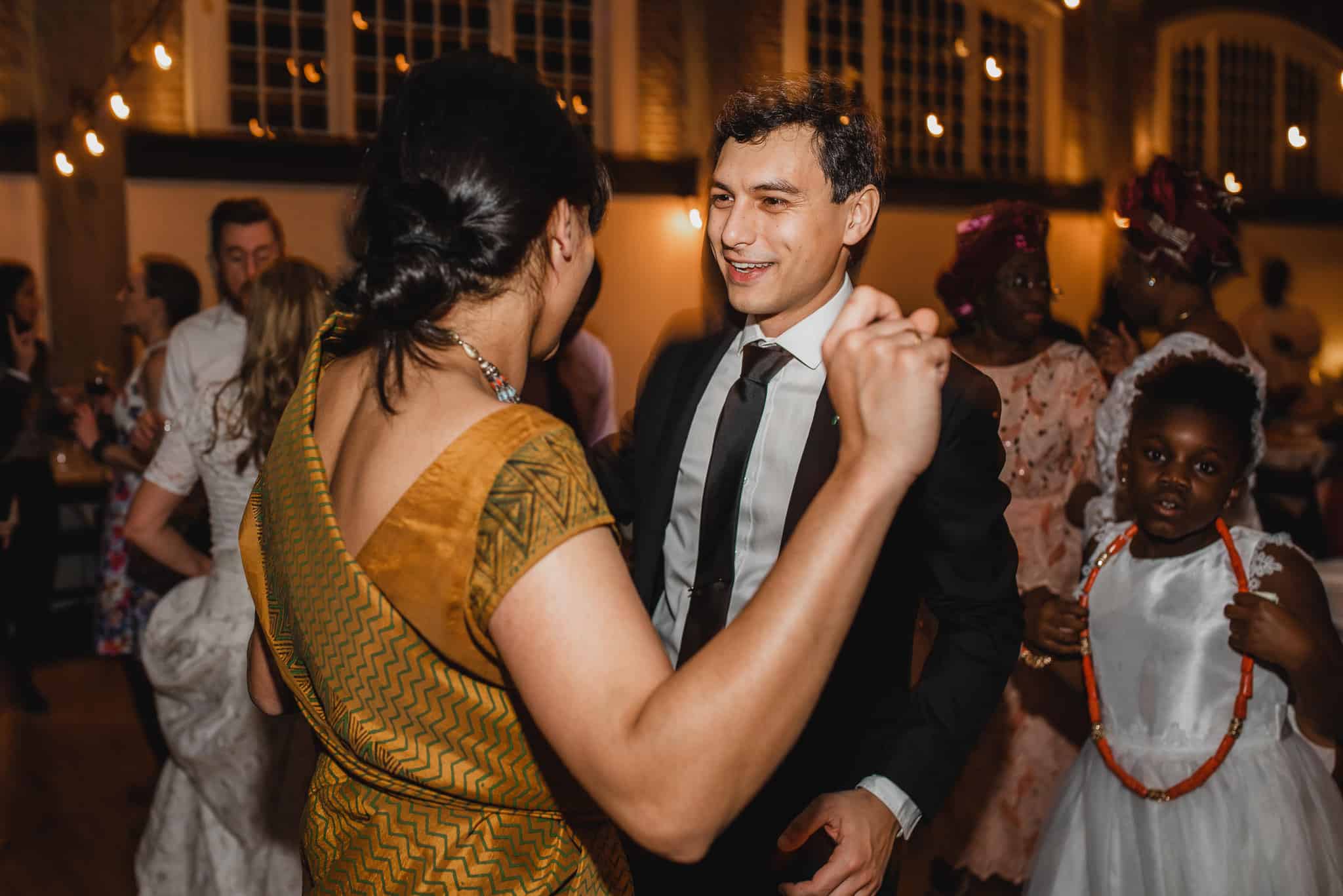 People dancing at a lively wedding at the Evergreen; a diverse group in formal attire, warm lighting, and joyful expressions create an unforgettable atmosphere.