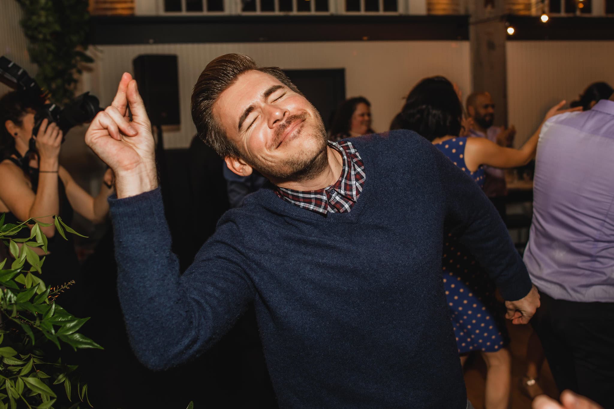 At a lively wedding at the Evergreen, a man dances with eyes closed and a broad smile, exuding pure joy.